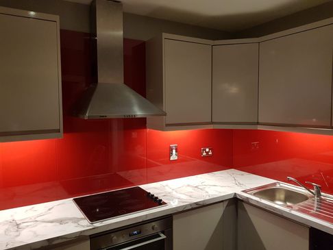 Red kitchen splashback with overhead lighting in a contemporary kitchen