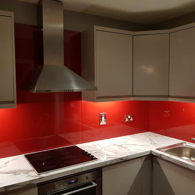Red kitchen splashback with overhead lighting in a contemporary kitchen